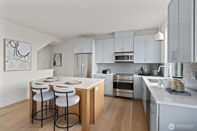 4519A Bagley Ave N, Seattle, WA 98103 - kitchen featuring stainless steel appliances, light wood-style floors, tasteful backsplash, a kitchen island, and a breakfast bar