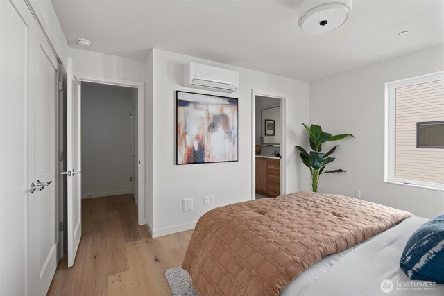 4519A Bagley Ave N, Seattle, WA 98103 - bedroom featuring a wall mounted AC, light wood finished floors, and connected bathroom