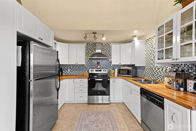 1291 Channel Ave SW, Ocean Shores, WA 98569 - kitchen with appliances with stainless steel finishes, wall chimney exhaust hood, wood counters, a sink, and tasteful backsplash