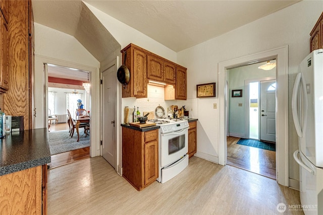 1324 E 2nd St, Port Angeles, WA 98362 - kitchen featuring white appliances, light wood-style flooring, dark countertops, brown cabinetry, and decorative backsplash