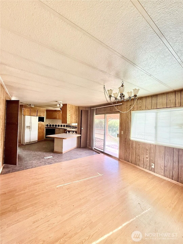 1485B Old Hwy 97, Malott, WA 98840 - unfurnished living room with a textured ceiling, wooden walls, light wood finished floors, and baseboards