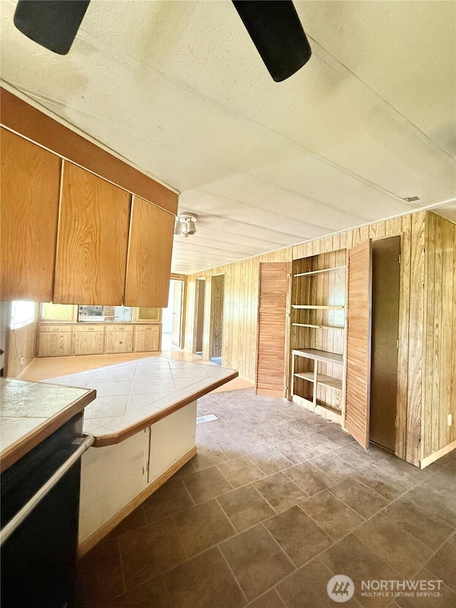 1485B Old Hwy 97, Malott, WA 98840 - kitchen featuring tile counters, wooden walls, built in shelves, and healthy amount of natural light
