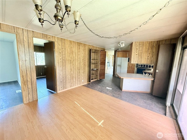 1485B Old Hwy 97, Malott, WA 98840 - kitchen with a chandelier, brown cabinetry, wood walls, white fridge with ice dispenser, and light countertops