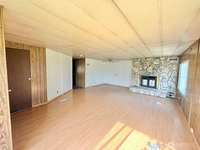 1485B Old Hwy 97, Malott, WA 98840 - unfurnished living room featuring wood finished floors, a ceiling fan, a stone fireplace, and wooden walls