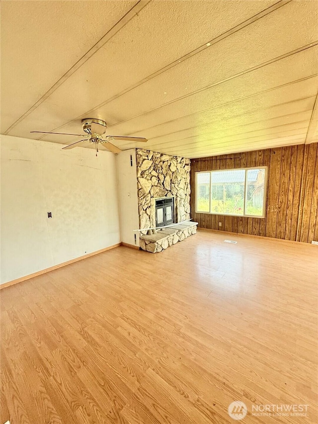 1485B Old Hwy 97, Malott, WA 98840 - unfurnished living room featuring wood finished floors, a textured ceiling, a fireplace, a ceiling fan, and wood walls