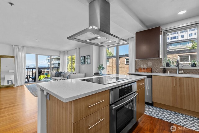 500 5th Ave W Unit 501, Seattle, WA 98119 - kitchen with stainless steel oven, wall chimney range hood, modern cabinets, a kitchen island, and plenty of natural light