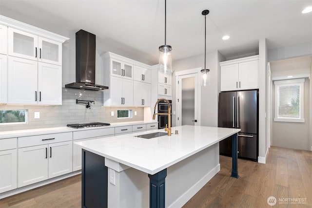 7547 S 130th Pl, Seattle, WA 98178 - kitchen with stainless steel appliances, wall chimney range hood, a sink, backsplash, and wood finished floors