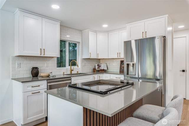 3718 W Arsenal Way, Bremerton, WA 98312 - kitchen with a sink, stainless steel appliances, a kitchen island, decorative backsplash, and a breakfast bar