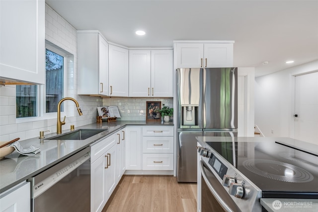 3718 W Arsenal Way, Bremerton, WA 98312 - kitchen with appliances with stainless steel finishes, a sink, white cabinets, light wood finished floors, and tasteful backsplash