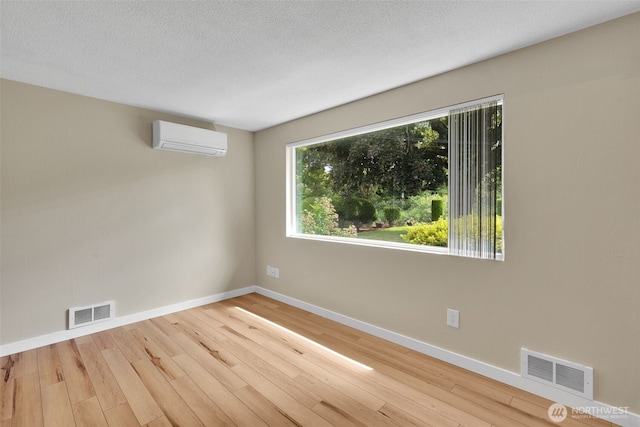 348 7th Pl SE Unit 1, Puyallup, WA 98372 - unfurnished room with a wall mounted air conditioner, hardwood / wood-style floors, and a textured ceiling