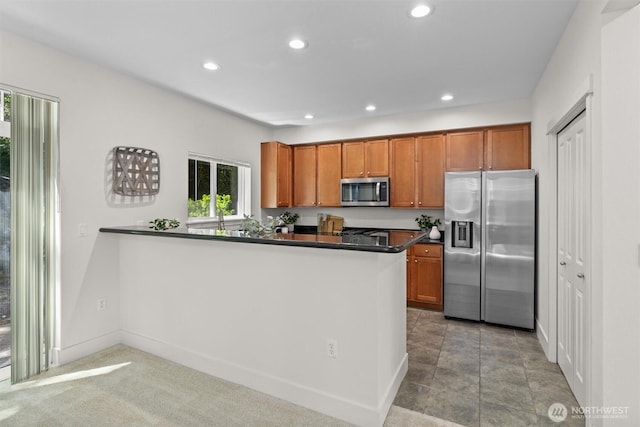 5529 Lakemont Blvd SE Unit 901, Bellevue, WA 98006 - kitchen featuring appliances with stainless steel finishes, dark countertops, brown cabinetry, recessed lighting, and a peninsula