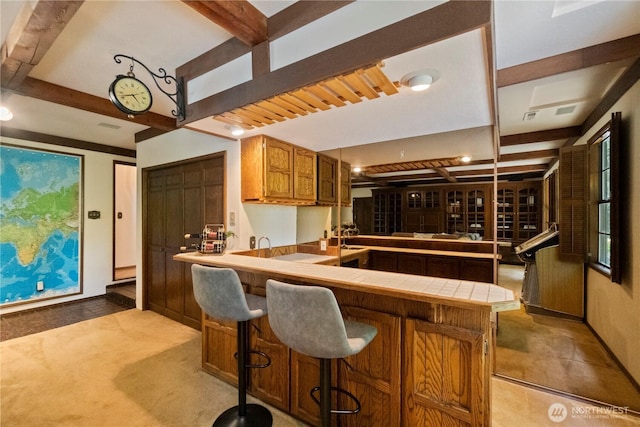 21102 31st Ave SE, Bothell, WA 98021 - kitchen with tile countertops, beam ceiling, brown cabinets, a peninsula, and baseboards