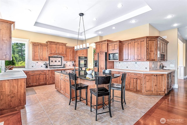 3178 Edgewood Ln, Bellingham, WA 98226 - kitchen with black appliances, a raised ceiling, an island with sink, brown cabinetry, and recessed lighting
