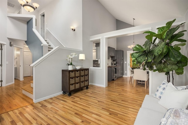 20160 Bue Rund Loop NE, Poulsbo, WA 98370 - living room with a chandelier, light wood-style floors, high vaulted ceiling, stairway, and baseboards