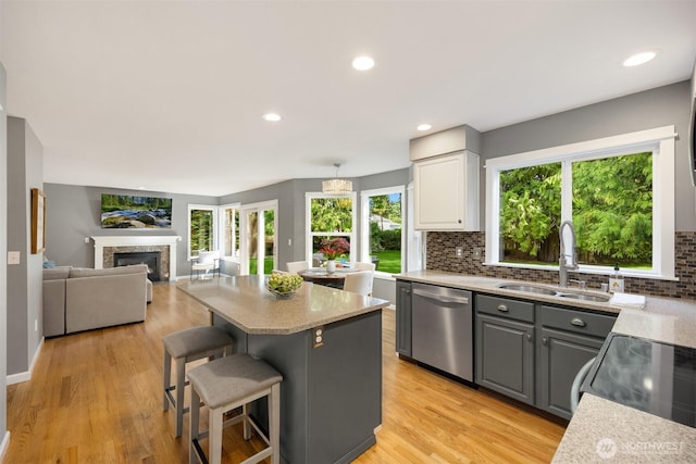 20160 Bue Rund Loop NE, Poulsbo, WA 98370 - kitchen with stainless steel dishwasher, a sink, gray cabinets, a kitchen island, and a glass covered fireplace