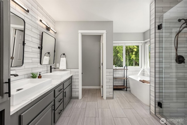 20160 Bue Rund Loop NE, Poulsbo, WA 98370 - bathroom featuring tile walls, double vanity, a freestanding bath, and a stall shower