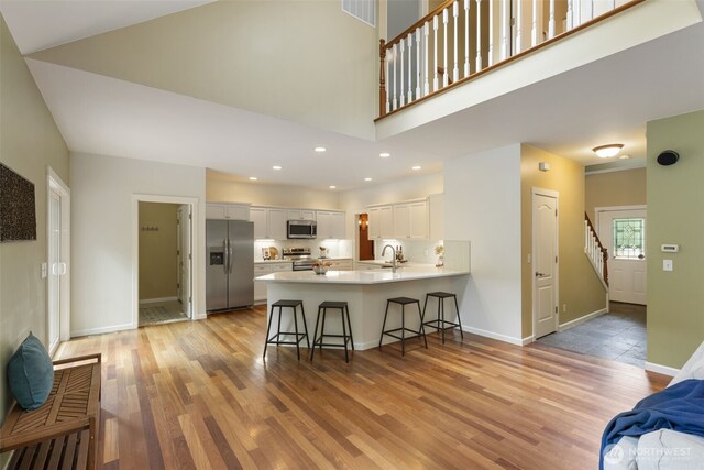 31199 Laughing Dog Ave NE, Poulsbo, WA 98370 - kitchen featuring appliances with stainless steel finishes, a peninsula, a kitchen bar, white cabinetry, and light countertops