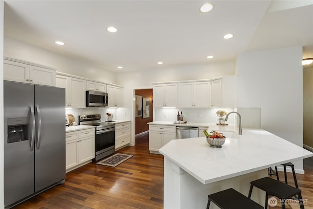 31199 Laughing Dog Ave NE, Poulsbo, WA 98370 - kitchen with stainless steel appliances, a peninsula, white cabinets, a kitchen bar, and tasteful backsplash