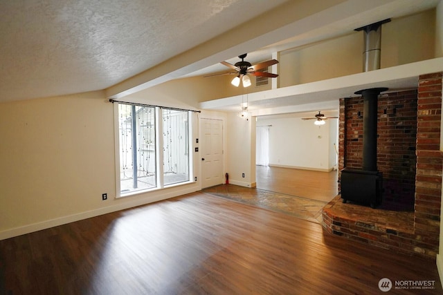463 Humble Hill Rd, Sequim, WA 98382 - unfurnished living room with baseboards, wood finished floors, a wood stove, ceiling fan, and a textured ceiling