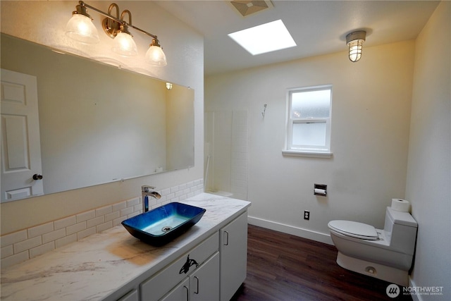 463 Humble Hill Rd, Sequim, WA 98382 - bathroom featuring vanity, tasteful backsplash, a skylight, toilet, and wood finished floors