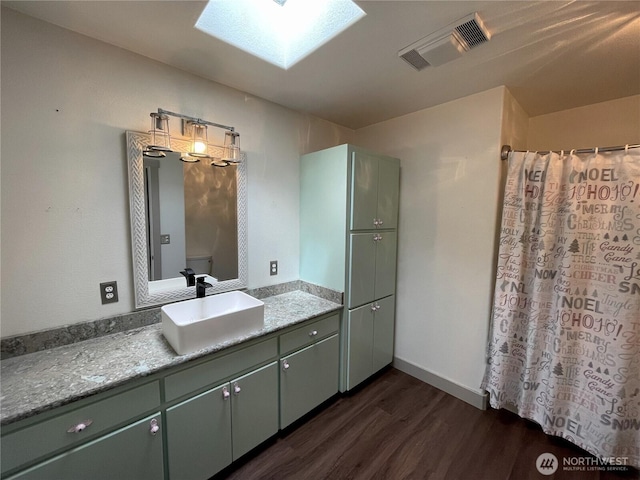 463 Humble Hill Rd, Sequim, WA 98382 - bathroom featuring wood finished floors, vanity, a skylight, curtained shower, and baseboards