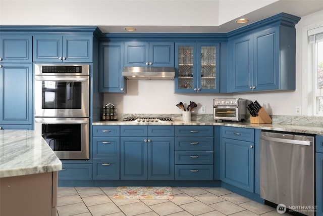 190 Twin Peaks Rd, Selah, WA 98942 - kitchen with stainless steel appliances, under cabinet range hood, blue cabinetry, light stone counters, and light tile patterned floors