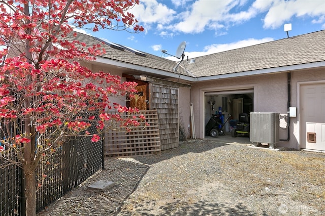 190 Twin Peaks Rd, Selah, WA 98942 - rear view of house featuring stucco siding, an attached garage, a shingled roof, and central air condition unit