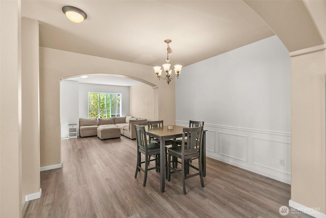 3007 Belmonte Ln, Everett, WA 98201 - dining room with arched walkways, wood finished floors, a chandelier, a wainscoted wall, and a decorative wall
