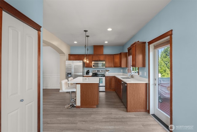 3007 Belmonte Ln, Everett, WA 98201 - kitchen with stainless steel appliances, a sink, arched walkways, light wood-style flooring, and a kitchen breakfast bar