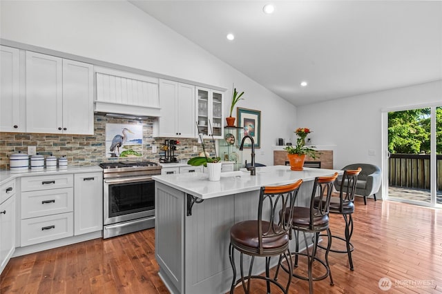 3016 97th Pl SE, Everett, WA 98208 - kitchen featuring gas stove, vaulted ceiling, backsplash, hardwood / wood-style floors, and a breakfast bar area