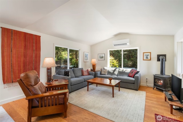 512 Snagstead Way, Port Townsend, WA 98368 - living area with a wall mounted air conditioner, vaulted ceiling, a wood stove, light wood finished floors, and baseboards