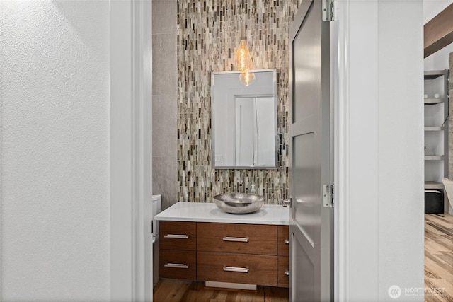 501 Maple Leaf Loop, Cle Elum, WA 98922 - half bathroom featuring vanity, wood finished floors, tasteful backsplash, tile walls, and toilet