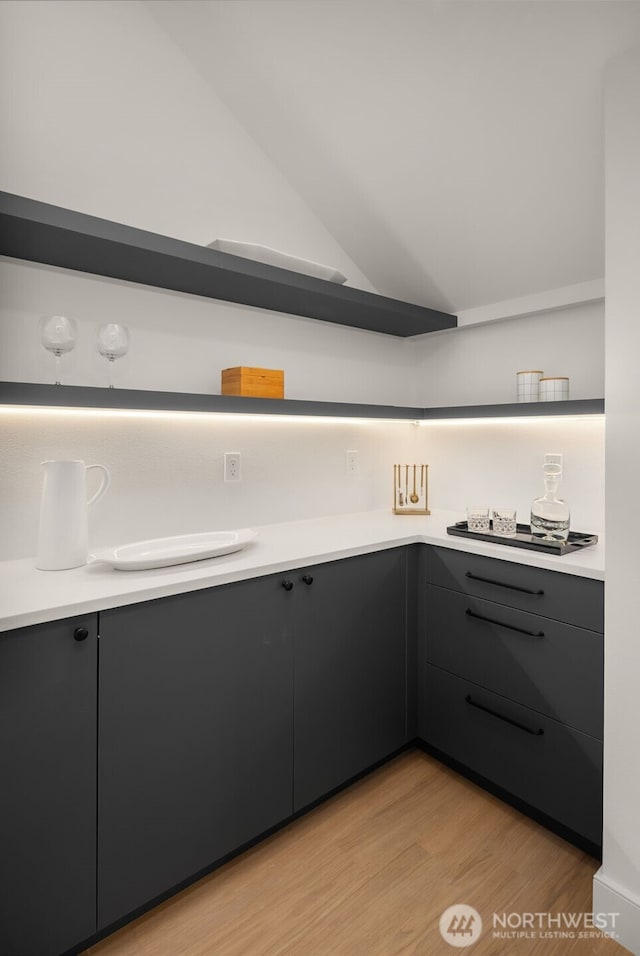 12833 NE 91st St, Kirkland, WA 98033 - kitchen with open shelves, light wood-type flooring, light countertops, black electric stovetop, and vaulted ceiling