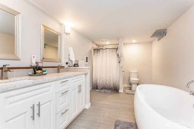 207 N Colville St, Walla Walla, WA 99362 - full bathroom featuring double vanity, a freestanding bath, a shower with curtain, wood finish floors, and toilet