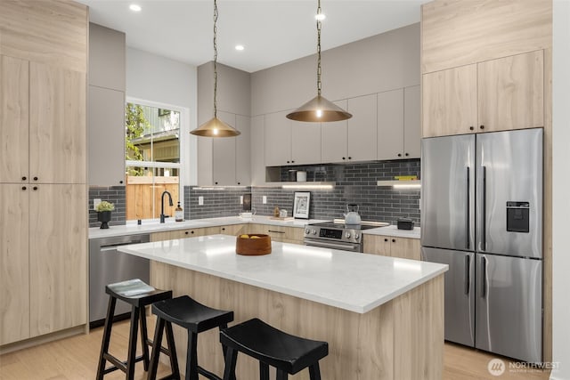 12837 NE 91st St, Kirkland, WA 98033 - kitchen with appliances with stainless steel finishes, a kitchen bar, light wood-style floors, decorative backsplash, and a kitchen island