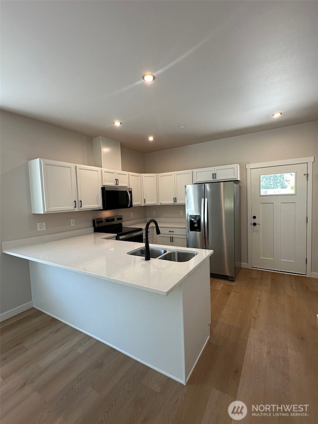 1712 Sunup Loop, Bellingham, WA 98226 - kitchen featuring appliances with stainless steel finishes, light wood-style flooring, a peninsula, light countertops, and white cabinets