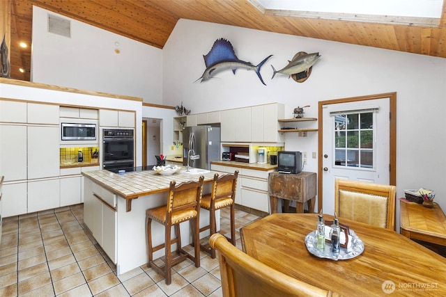 280 Surf St, Westport, WA 98595 - kitchen with stainless steel appliances, tile countertops, a kitchen island, light tile patterned floors, and white cabinetry
