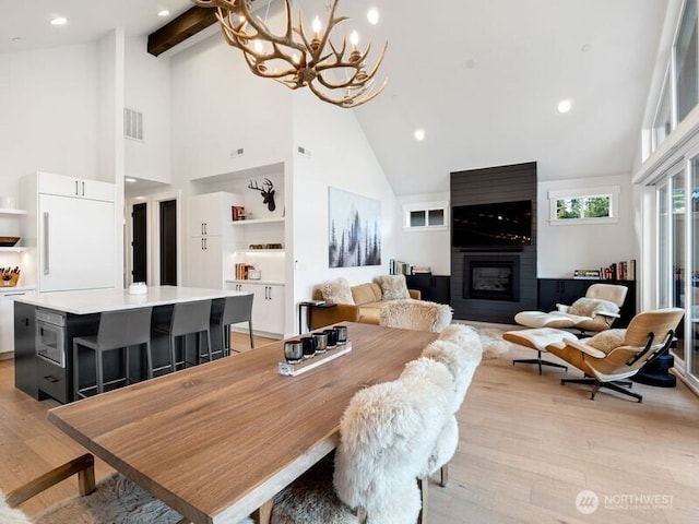 30 Symphony Ct, Cle Elum, WA 98922 - dining space with high vaulted ceiling, light wood finished floors, a chandelier, a fireplace, and beamed ceiling