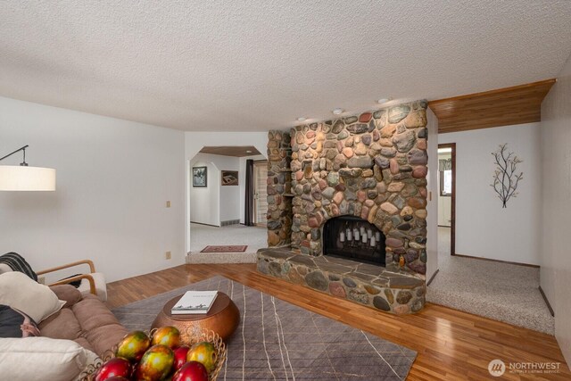 710 S Mckinney Rd, Othello, WA 99344 - living room featuring wood finished floors, a textured ceiling, and a stone fireplace
