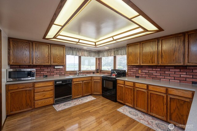 710 S Mckinney Rd, Othello, WA 99344 - kitchen with black appliances, a sink, brown cabinetry, and light countertops