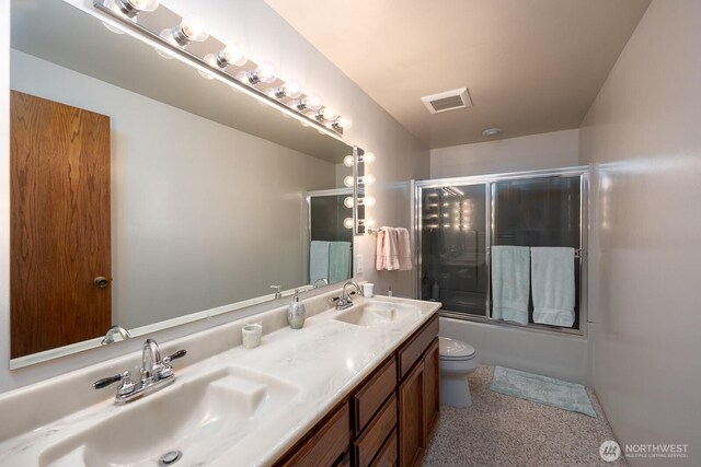710 S Mckinney Rd, Othello, WA 99344 - full bathroom featuring toilet, double vanity, and bath / shower combo with glass door