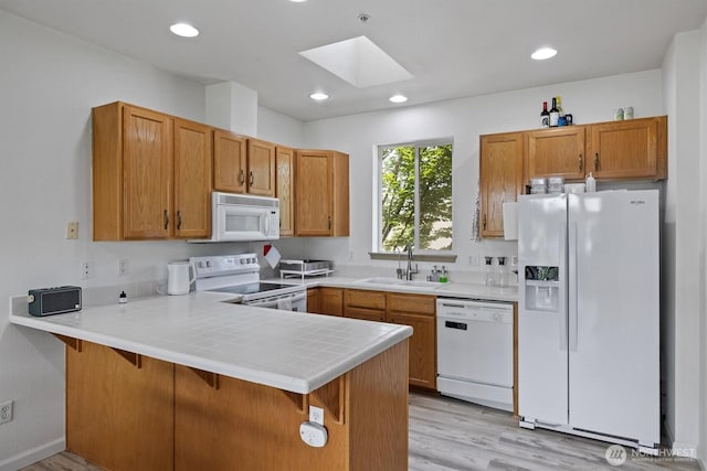 2311 Milton Way Unit E, Milton, WA 98354 - kitchen with white appliances, a sink, a skylight, a peninsula, and light wood-style flooring