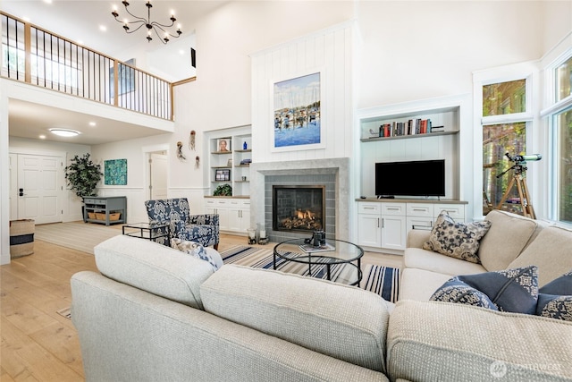 5552 Canvasback Rd, Blaine, WA 98230 - living area with a high ceiling, light wood finished floors, built in shelves, a chandelier, and a tile fireplace