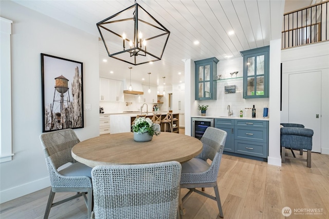 5552 Canvasback Rd, Blaine, WA 98230 - dining area with light wood-type flooring, bar with sink, beverage cooler, a chandelier, and baseboards