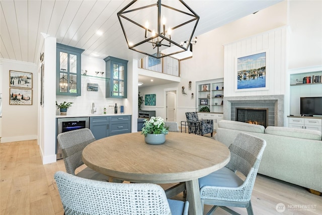 5552 Canvasback Rd, Blaine, WA 98230 - dining room with wine cooler, a lit fireplace, light wood-type flooring, bar area, and a chandelier