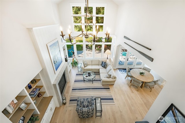 5552 Canvasback Rd, Blaine, WA 98230 - living area featuring wood finished floors, a towering ceiling, a chandelier, and a fireplace with flush hearth