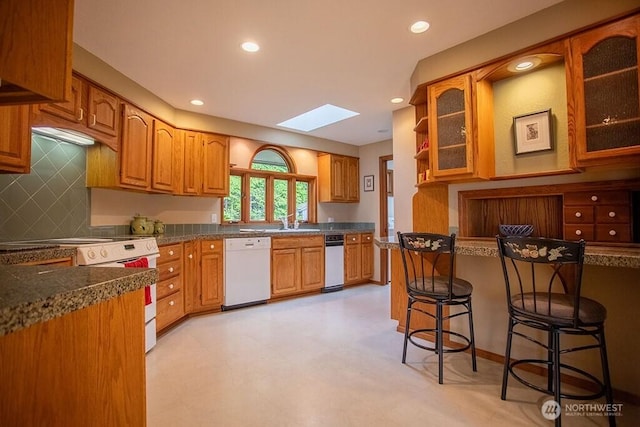 12289 Seabeck Hwy NW, Seabeck, WA 98380 - kitchen featuring white appliances, a skylight, a breakfast bar, glass insert cabinets, and brown cabinetry