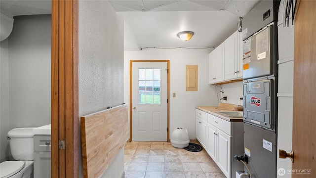 810 E Spring, Dayton, WA 99328 - laundry area with electric panel, a textured wall, a sink, and light stone finish floors