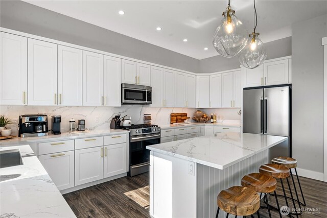 1401 S Cohasset Crst, Westport, WA 98595 - kitchen featuring stainless steel appliances, dark wood-style floors, a kitchen island, a breakfast bar, and white cabinets