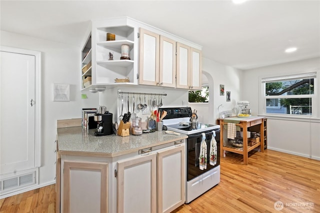 4325 E B St, Tacoma, WA 98404 - kitchen with electric range oven, arched walkways, light wood finished floors, open shelves, and white cabinetry